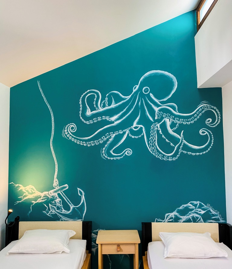 Blaue Wand mit einer Wandmalerei, auf der ein Oktopus zu sehen ist.