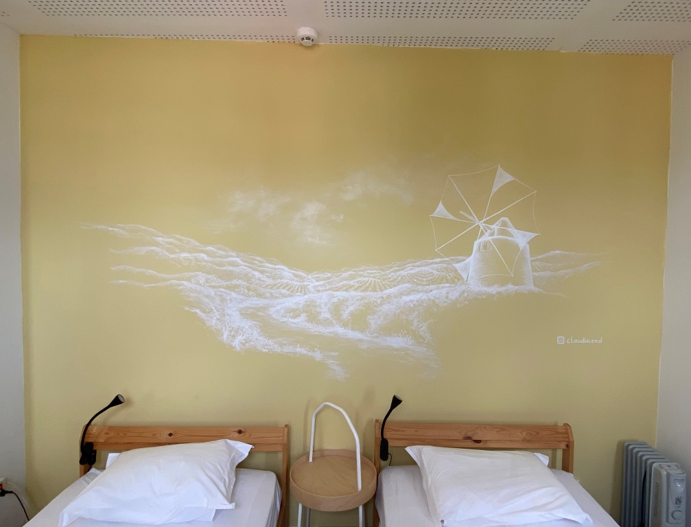 Zimmergestaltung mit gelber Wand und Wandgemälde mit einer Windmühle.