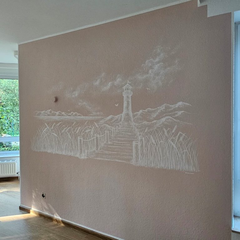 Zimmer mit rosafarbener Wand und einem weißen Strand- und Leuchtturmmotiv.