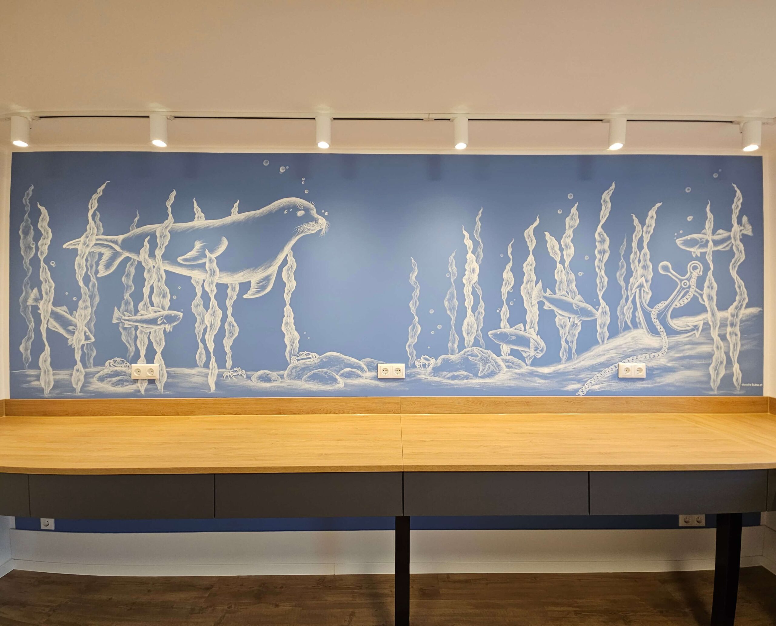 Auf der Wandmalerei ist eine Unterwasserwelt mit einem Seehund, Fischen, Algen, Krebsen und einem Anker zu sehen.