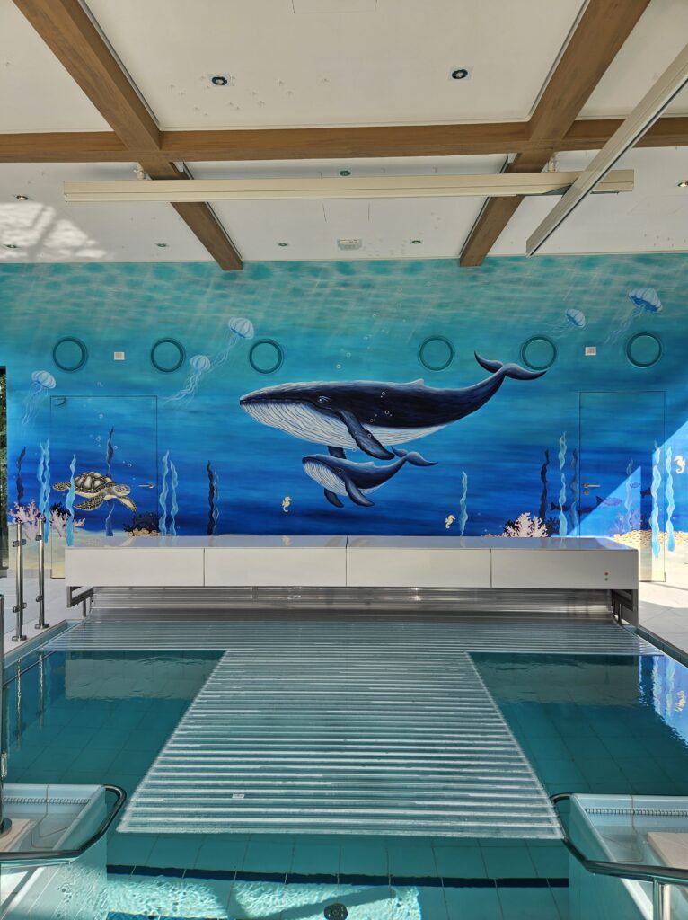 Wandgemälde "Wale" Wandgestaltung im Therapiebad des Kinderhospizes "Sternenbrücke" in Rissen. Zu sehen sind zwei Wale, Quallen, eine Schildkröte und verschiedene Unterwasserpflanzen.