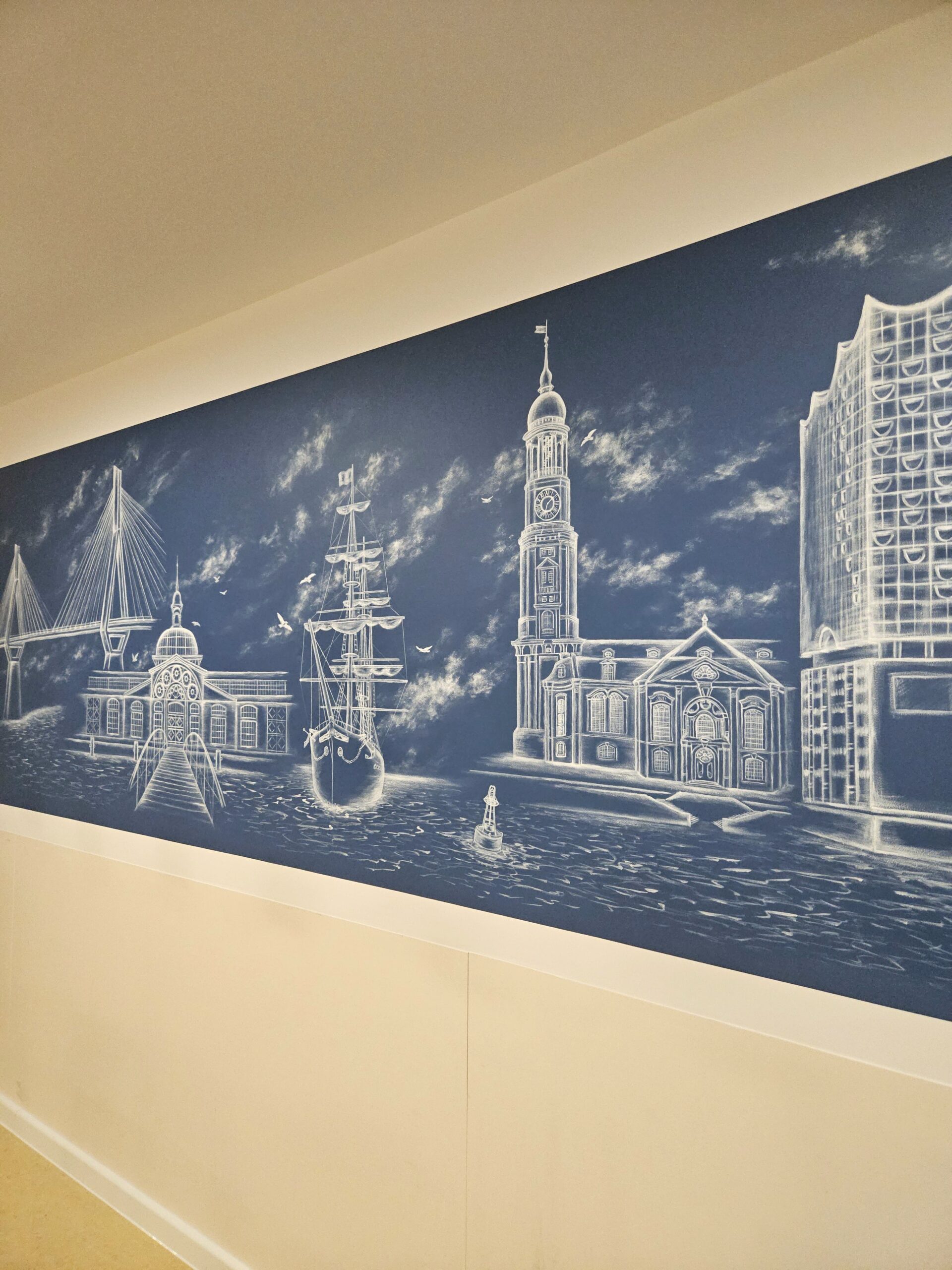 Detaillierte Malerei auf blauem Untergrund. Dargestellt sind Sehenswürdigkeiten der Stadt Hamburg. Die Wandmalerei ziert einen Aufenthaltsraum im Agaplesion-Krankenhaus in der Hansestadt.