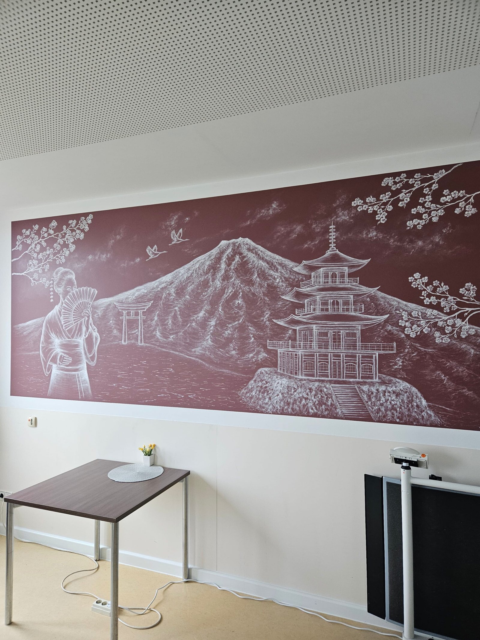 Japanisch inspiriertes Wandgemälde auf der geriatrischen Station des Agaplesion Diakonieklinikums Hamburg. Dargestellt sind eine Geisha, Mandschurenkraniche, ein Torii-Tor, der Berg Fuji und eine Pagode. Das Wandbild wurde im Zuge der Neugestaltung der Station geschaffen und trägt zu einer ruhigen, freundlichen Atmosphäre für Patientinnen und Patienten, Angehörige sowie das Klinikteam bei.
